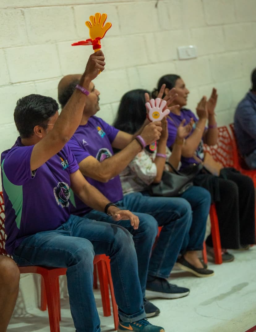 Parents cheering courtside with clappers at a Pitch Youth League game